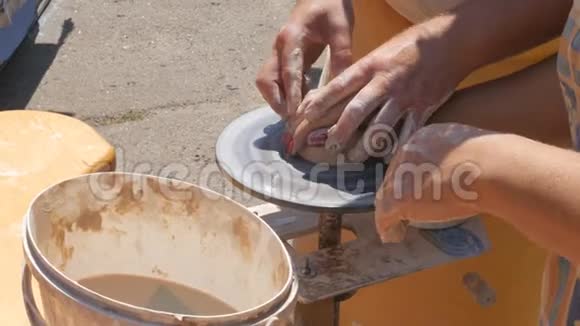 这位雕刻家陶工在街上用粘土做水壶特写扭曲锅的车轮视频的预览图