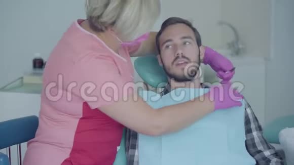 牙医戴着医用口罩和手套准备病人检查向医生解释他的问题女性视频的预览图