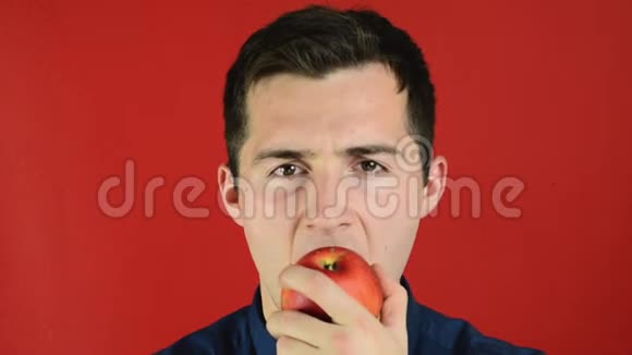 站在红色背景下微笑着吃苹果的人视频的预览图