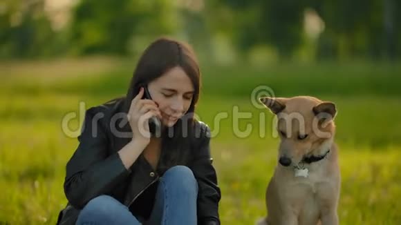 女孩在公园里和一只狗散步时打电话视频的预览图