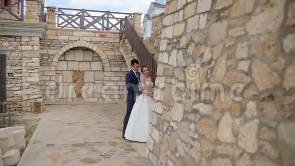一对年轻夫妇在一座漂亮的城堡和石墙旁边摆姿势拍照石墙上有一个石楼梯视频的预览图