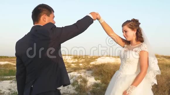 情侣们在蓝天背景下的夏日公园里跳舞新娘新郎蜜月旅行视频的预览图