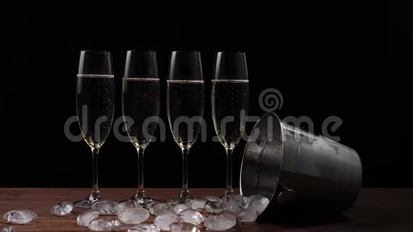 好香槟酒四杯金香槟酒和冰桶在黑色背景下散落在桌子上视频的预览图