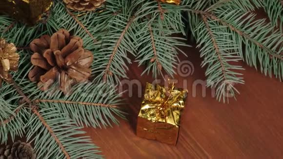 新年和圣诞节装饰一些礼物和松果靠近圣诞树树枝在棕色的木桌上视频的预览图