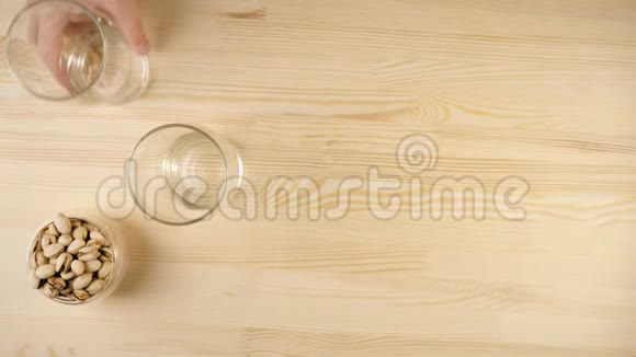 新鲜啤酒手把一个空杯子放在另一个玻璃旁边碟子里放着开心果放在背景的木桌上视频的预览图