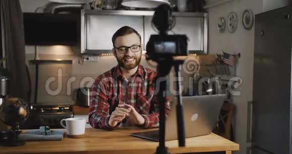 快乐年轻的微笑科技博客男子制作vlog视频流与专业相机在家厨房慢动作视频的预览图
