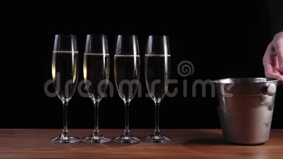 好香槟酒手翻了一个冰桶靠近四个玻璃杯上面有金色香槟冰撒在桌子上视频的预览图