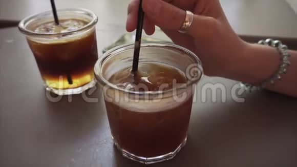 女孩在加浓咖啡的杯子里搅拌冰吃覆盆子通心粉视频的预览图