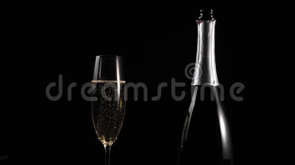 好香槟酒用一杯金色香槟在黑底木桌上的另一个杯子里手一碰视频的预览图