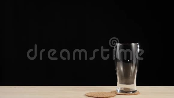新鲜啤酒手把第二个啤酒杯放在靠近第一个杯子的啤酒杯上放在黑色背景的木桌上视频的预览图