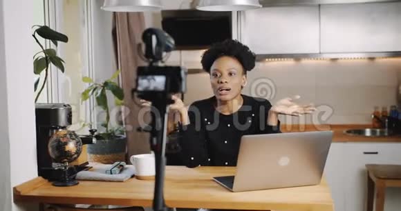 快乐年轻有吸引力的非洲视频博主使用专业相机在家厨房慢动作录制新的vlog视频的预览图