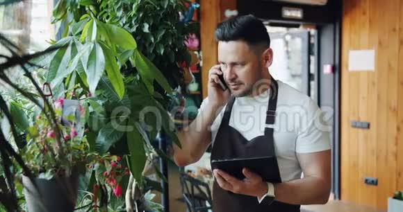 快乐的人花店在手机上聊天拿着平板电脑看着绿植视频的预览图