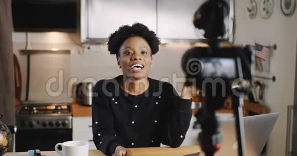 快乐年轻成功女性黑vlogger为博客制作新视频使用专业相机在家慢动作视频的预览图