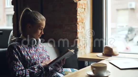 美丽的年轻女子在咖啡馆里读着有趣的书笑着视频的预览图