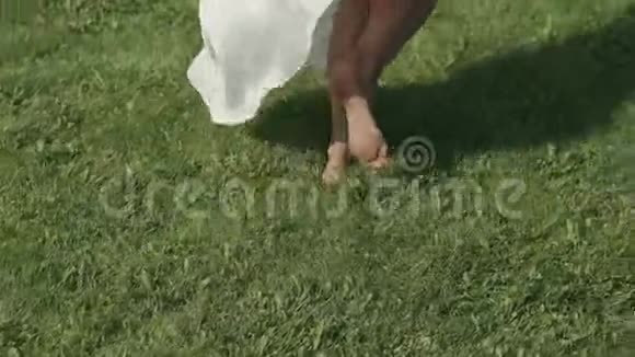特写一个在草地上奔跑的女孩的赤脚服饰在风中发展视频的预览图