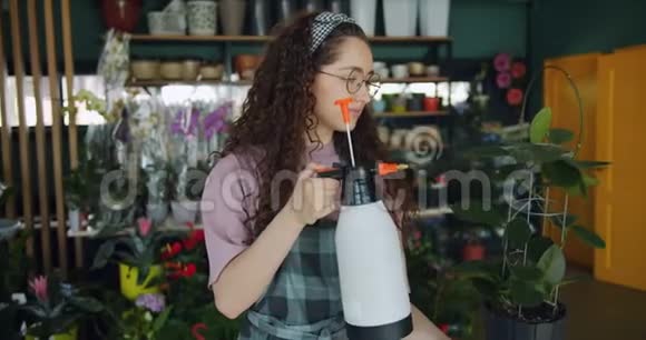 微笑的年轻花店用喷瓶机处理绿植浇水视频的预览图