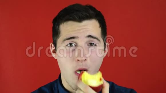 站在红色背景下微笑着吃苹果的人视频的预览图