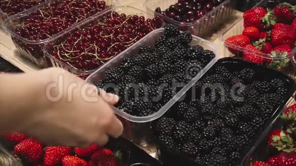 素食女孩在超市的商店柜台上选择新鲜的有机黑莓视频的预览图