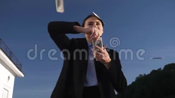 年轻成功的女商人穿着西装在大街上乱扔钱下雨下雨美元贬值视频的预览图