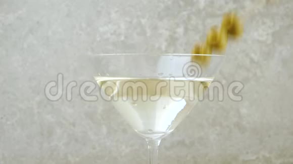 豪华马提尼三个美味的绿橄榄放在鸡尾酒棒上与马提尼酒一起倒在玻璃杯里以防光线照射视频的预览图
