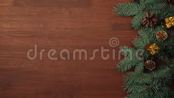 新年和圣诞节装饰手把一些礼物和松果放在一张棕色木桌上的圣诞树树枝上视频的预览图