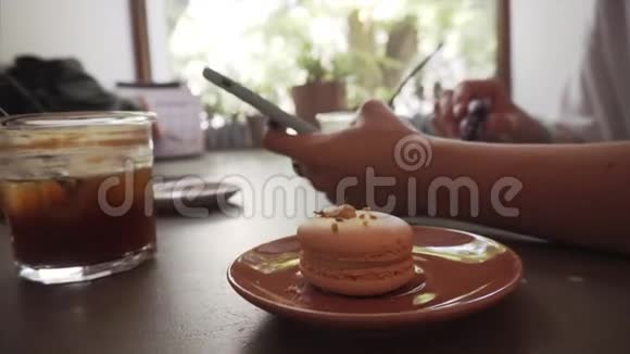 女孩坐在咖啡馆里用智能手机吃法国通心粉视频的预览图