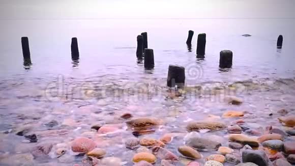 粉红色日落时港口的波兰瞭望塔下的木杆波涛汹涌的大海视频的预览图