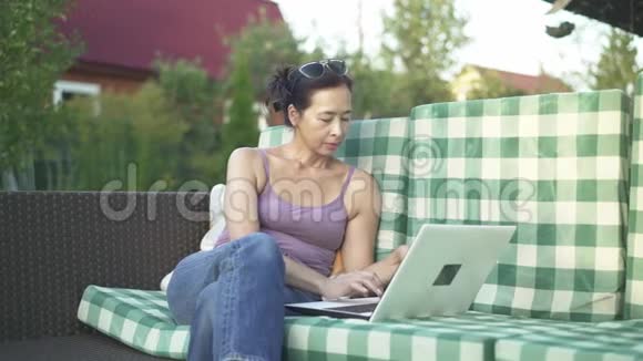 在院子里打手提电脑的亚洲女人视频的预览图