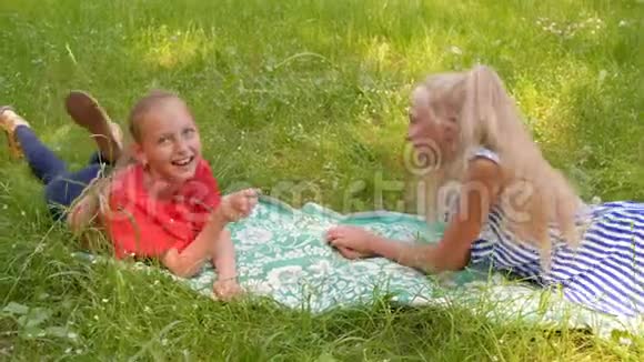 快乐的少年女孩躺在夏日的草地上有趣的女孩在夏天的草地上休息时玩草叶视频的预览图