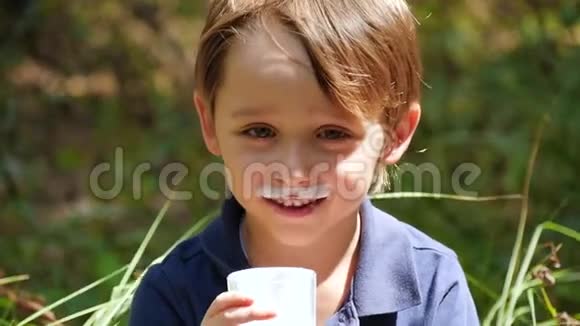 一个快乐的户外男孩喜欢慢动作地从一个透明的玻璃杯子里喝奶制品中的开菲尔视频的预览图
