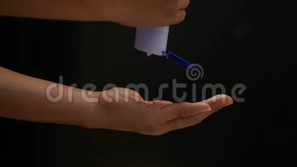 女人的手将身体护理乳液从瓶子中倒入她的手隔离在黑色背景上护肤理念视频的预览图