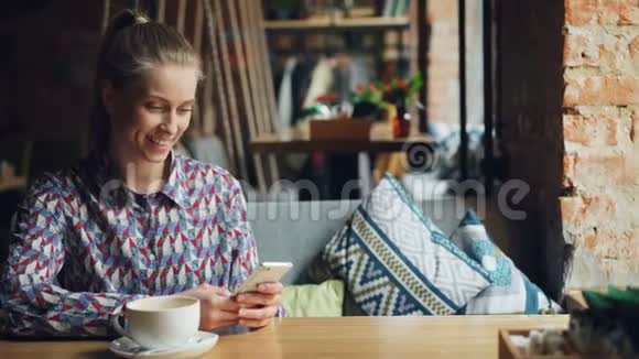 在咖啡馆里一个能触摸智能手机屏幕的快乐女孩在说话视频的预览图