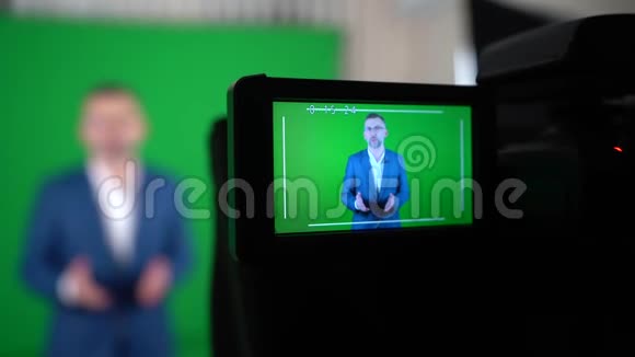 一个博主正在绿色背景上录制视频摄像机正在记录一个博主视频的预览图
