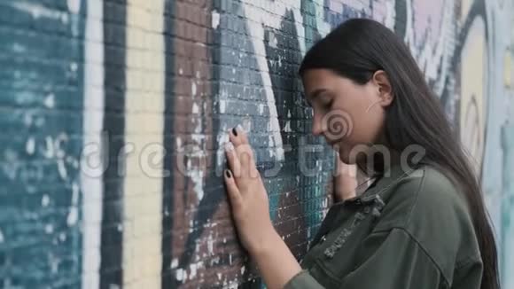 漂亮的时髦女孩在墙边涂鸦手放在墙上视频的预览图