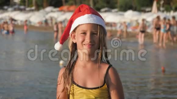 戴着红色圣诞帽的小可爱女孩在海滩上玩得很开心视频的预览图