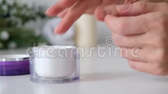 女人把奶油涂在她的手上白色的背景特写水疗化妆品视频的预览图