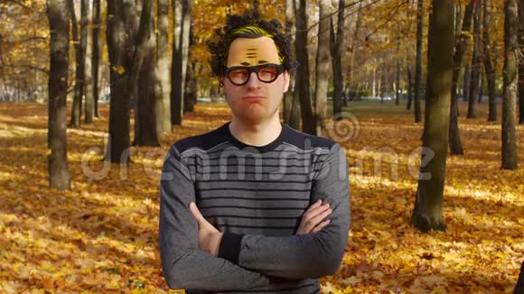 惊讶而睁着眼睛的卷发男子滑稽欢快的人类情绪秋天的公园阳光明媚的一天一片树叶飘落在小镇上视频的预览图