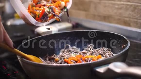蔬菜海鲜和酱料加入灶上煮熟的面条中视频的预览图