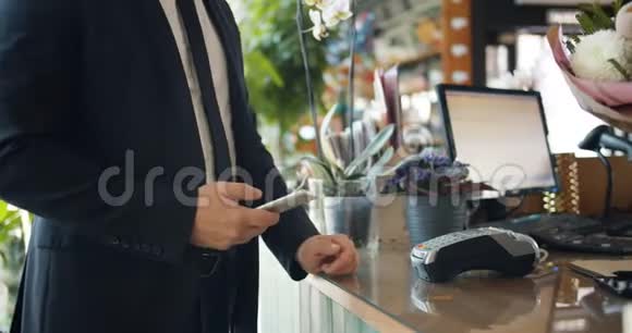 男人用智能手机在花店付款然后拿花束视频的预览图