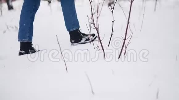 穿着黑色皮靴的女性脚在下雪的公园里散步女人踩雪享受圣诞假期龙龙视频的预览图