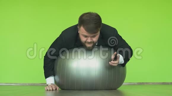 老板或老板躺在健身房的健身球上听电话交谈脂肪经理解决问题视频的预览图