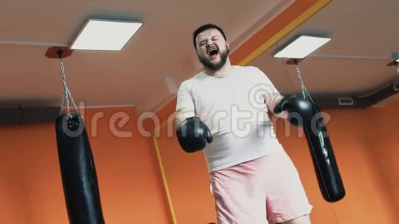 一个胖汗的家伙训练后累了在健身房脱下拳击手套丰满男子个人减肥训练视频的预览图