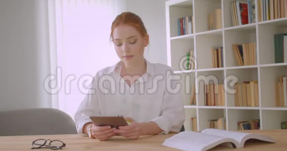使用平板电脑拍摄年轻漂亮红头发的女学生的特写肖像并在镜头前显示绿色屏幕视频的预览图