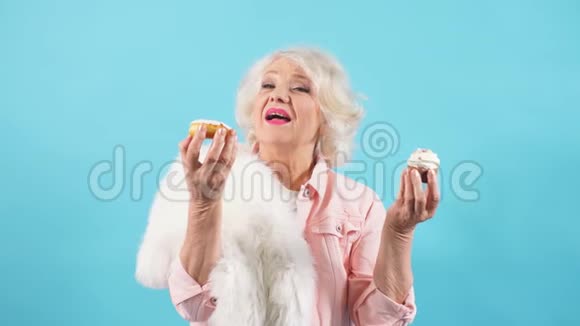 年长快乐开朗的女人手里拿着蛋糕手里拿着松饼视频的预览图