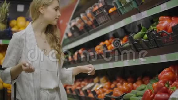 在超市里挑选黄瓜和蔬菜的女人购物选择购买水果蔬菜少女视频的预览图