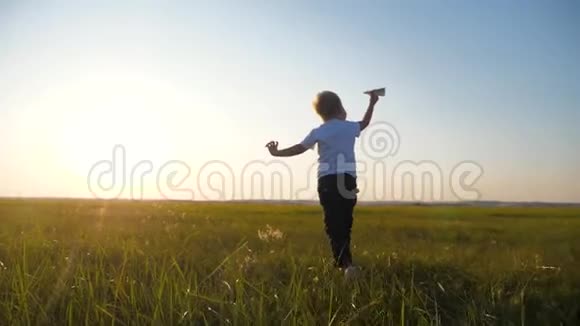 一个金发小男孩跑过绿色新鲜的草地手里拿着一架纸飞机孩子梦想飞翔视频的预览图