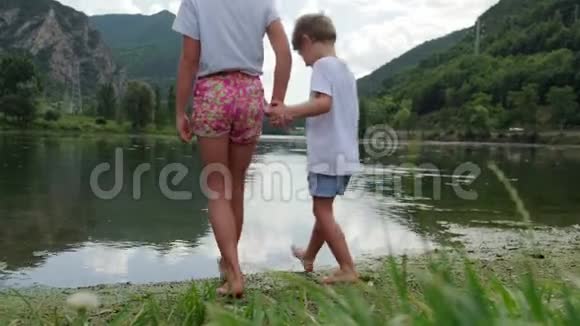 阴天时两个孩子手牵手朝山湖走去视频的预览图