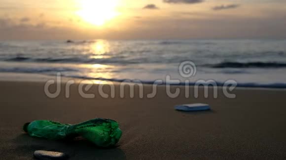 海浪和日落地平线背景下的海岸塑料瓶视频的预览图