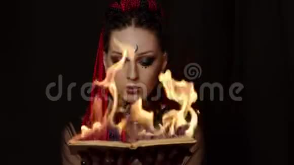 带辫子拿着燃烧的书的纹身女人的正面景色视频的预览图