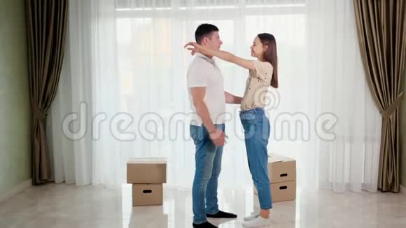 一对穿着蓝色牛仔裤的情侣在新房里拥抱亲吻视频的预览图